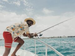 Smiling man fishing on a yacht in sunny weather, enjoying leisure in vibrant tropical waters., tags: moderne kurze - pexel
